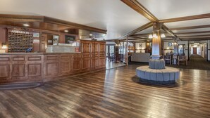 Un hall d’entrée spacieux avec un comptoir d’accueil en bois, un meuble à vin et un espace salon central.