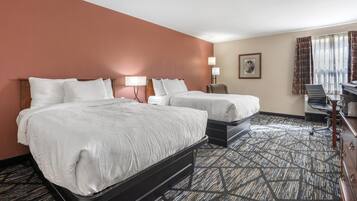 A hotel room with two beds, a desk, and a chair.