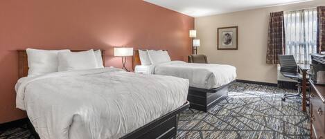 A hotel room with two beds, a desk, and a chair.