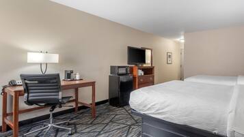 A hotel room with a bed, a desk with a chair, a television, a microwave, and a coffee maker.