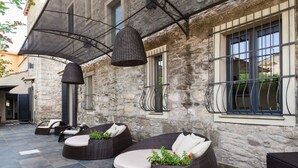 An outdoor seating area with wicker furniture and a stone building in the background. - Borgo Antico XIX sec (Gesturi)