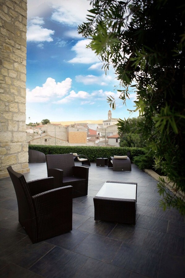 An outdoor patio with wicker furniture and a view of a cityscape. - Borgo Antico XIX sec (Gesturi)
