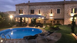A stone building with a swimming pool, outdoor seating, and a covered patio area. - Borgo Antico XIX sec (Gesturi)