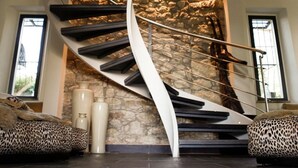 A modern spiral staircase with a stone wall behind it. - Borgo Antico XIX sec (Gesturi)