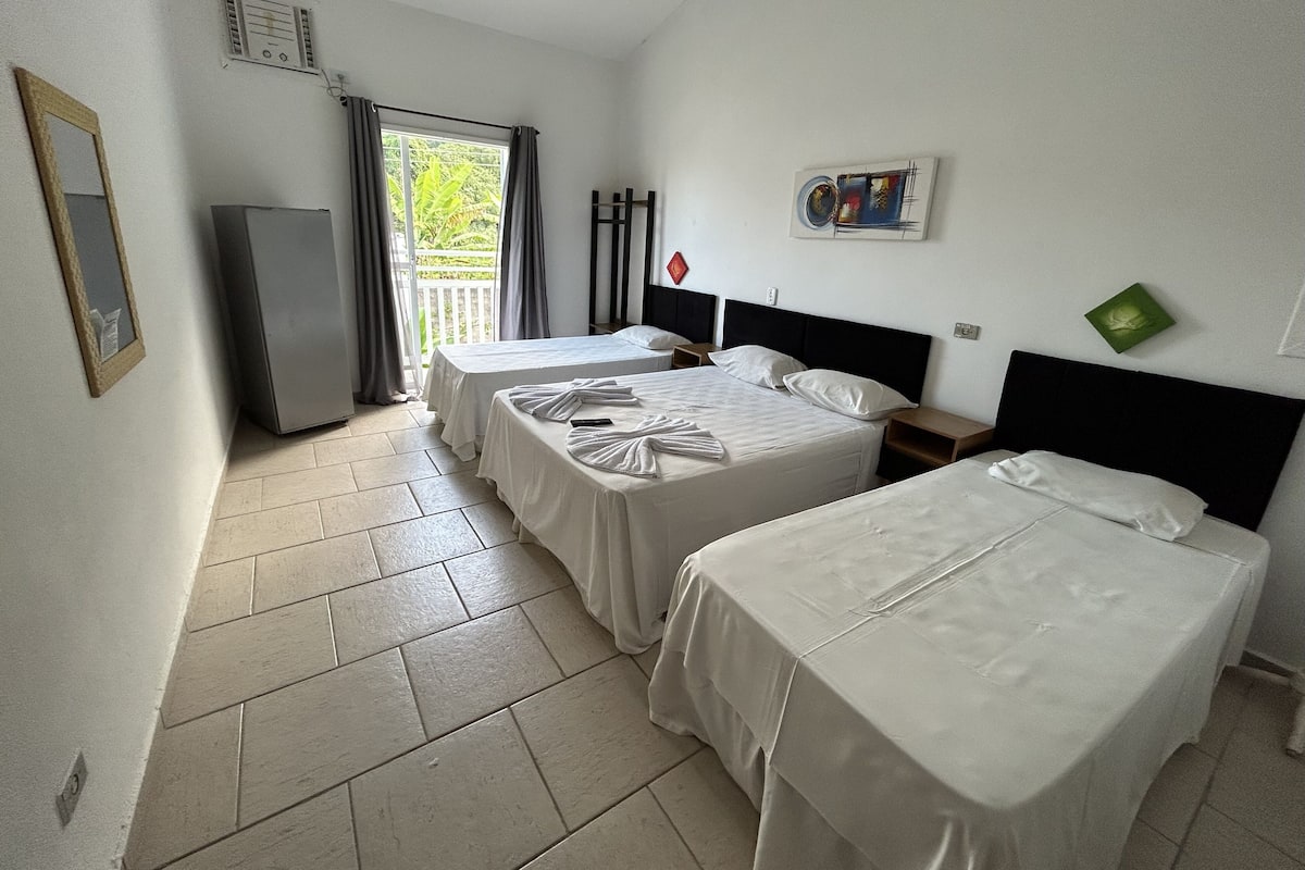 Ein Hotelzimmer mit zwei Einzelbetten, einem kleinen Tisch, einem Stuhl, einem Fernseher und einem Fenster mit Vorhängen.