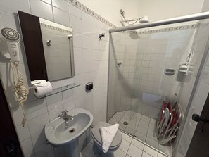 A bathroom with a sink, toilet, and a glass-enclosed shower area. - Pousada Vila Real Juquehy (São Sebastião)