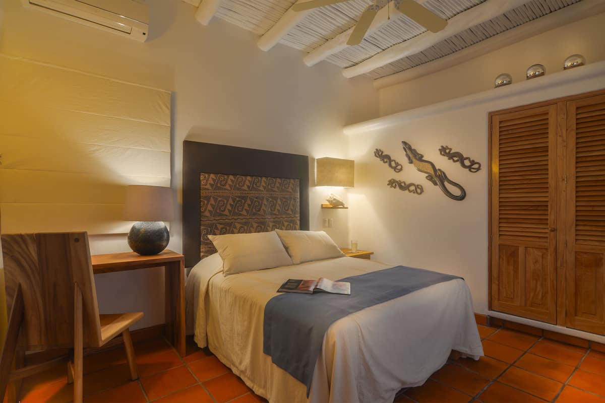 Un dormitorio con cama, una silla, una mesita de noche, una lámpara y un armario.