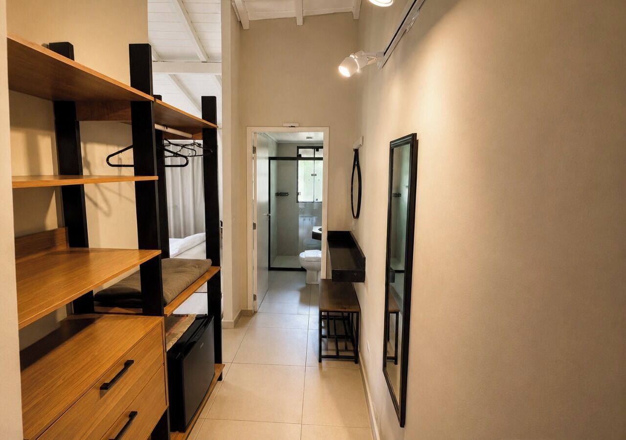 A narrow hallway with wooden shelving units, a bench, and a door leading to a bathroom.
