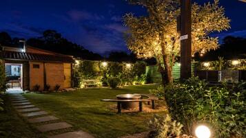 A well-lit outdoor area with a paved path leading to a building, a round table, and potted plants.