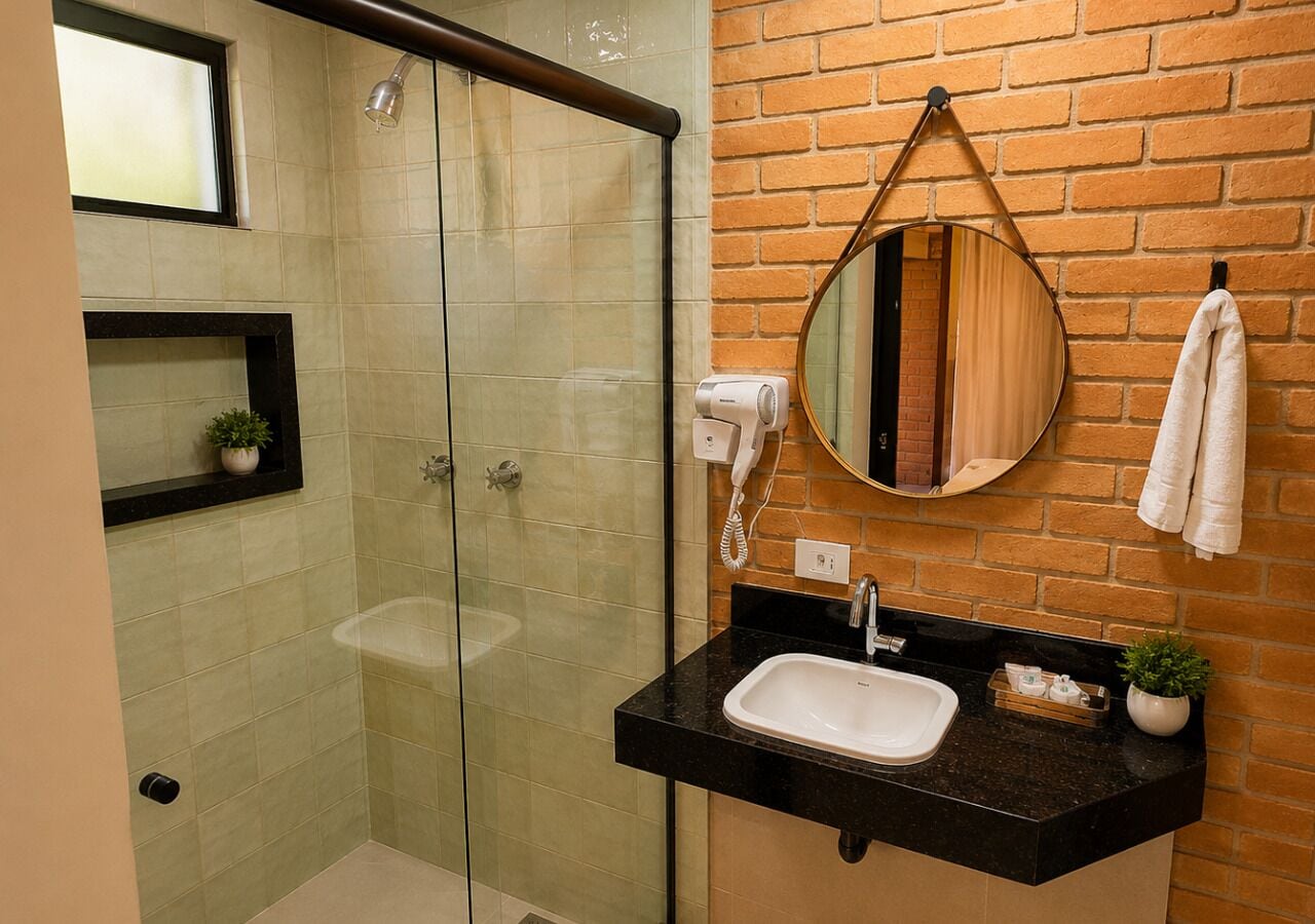 A bathroom with a glass-enclosed shower, a black countertop sink, a mirror, and a towel rack.