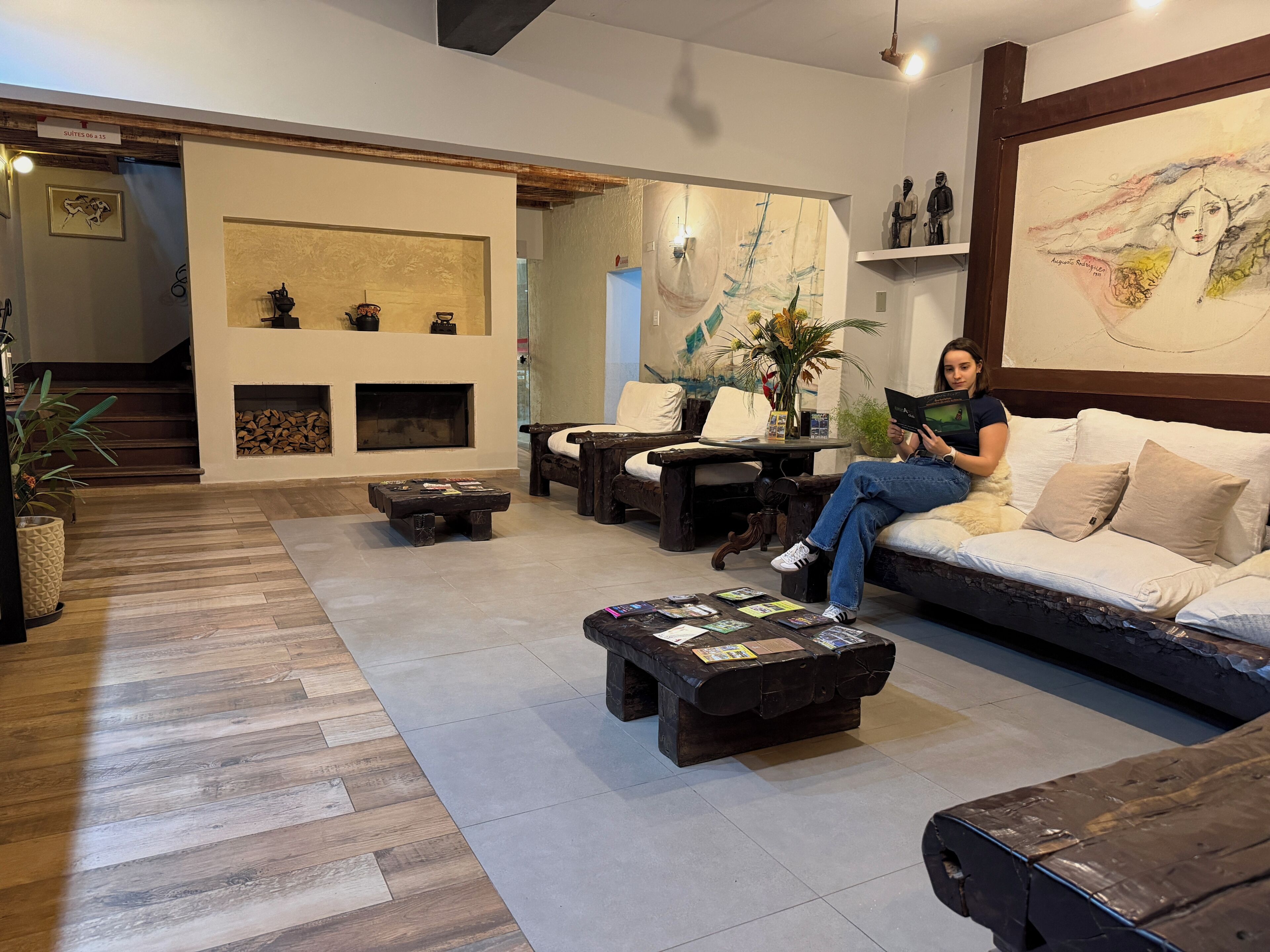 Una sala de estar moderna con sofá, mesa de centro y chimenea. Se ve una escalera que sube a otro nivel.