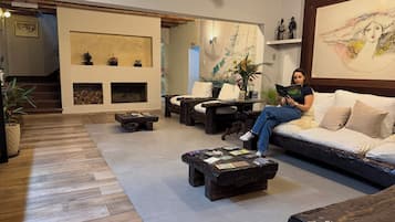 Una sala de estar moderna con sofá, mesa de centro y chimenea. Se ve una escalera que sube a otro nivel.
