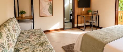 Un dormitorio con cama, sofá, escritorio y televisor.