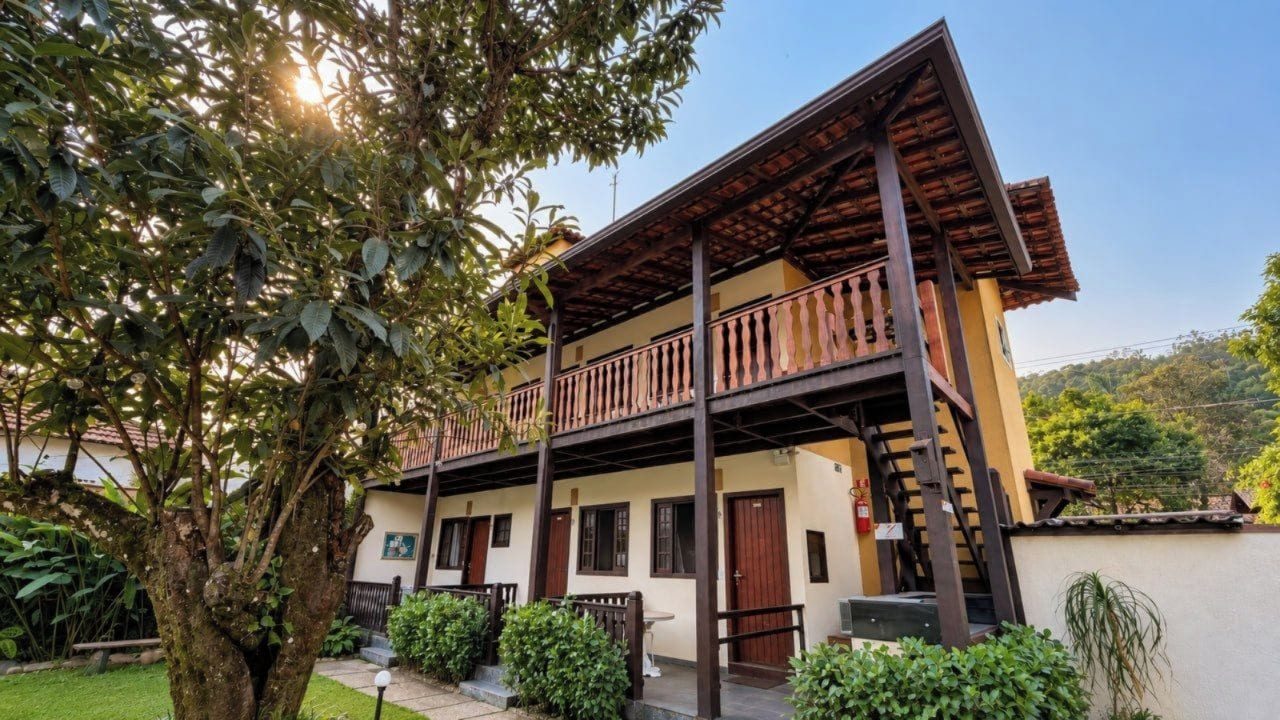 A two-story building with a balcony, surrounded by greenery.