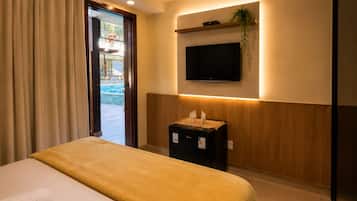 Una habitación de hotel con una cama, un televisor montado en la pared y una mesita con una planta.