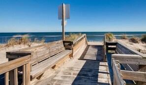 A wooden boardwalk leading to a beach with a clear sky.