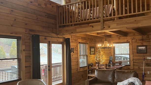 A spacious cabin with a loft bedroom, wooden floors, and a dining area with a fireplace. - Deep Creek Overlook Cabin HGTV Log Cabin Living WiFi Pool Table Hot Tub King Bed (Bryson City)