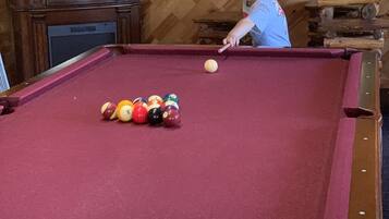 A pool table with balls, a television, and wooden paneling.