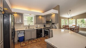 A kitchen with a large island, built-in appliances, and a dining area with chairs and a table. - Garret's Place by Hauserman Rental Group (Tahoe City)