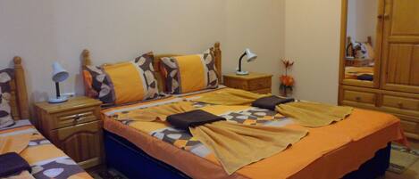 A bedroom with a bed, bedside tables, a nightstand, a lamp, a mirror, and a painting on the wall.