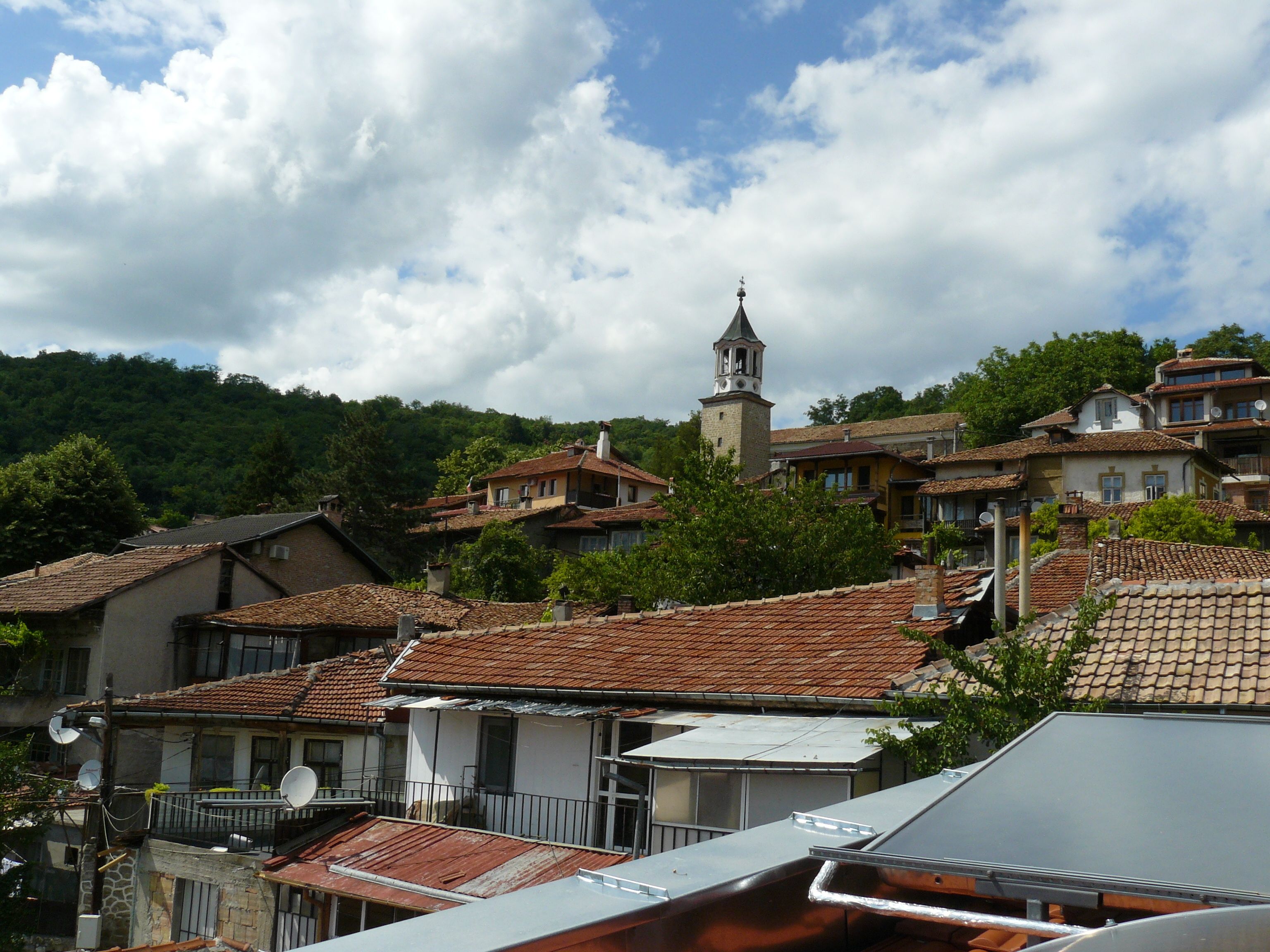 A hillside village with traditional buildings, a church tower, and a mix of residential and possibly commercial structures.