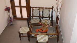 Una habitación con una silla y una mesa de madera, un florero con flores, y una puerta con paneles de vidrio.