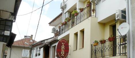 A building with a sign for 'House Varushka' and balconies with potted plants.