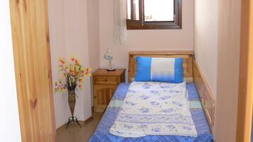 A bedroom with a bed, a nightstand, a window, and a radiator.