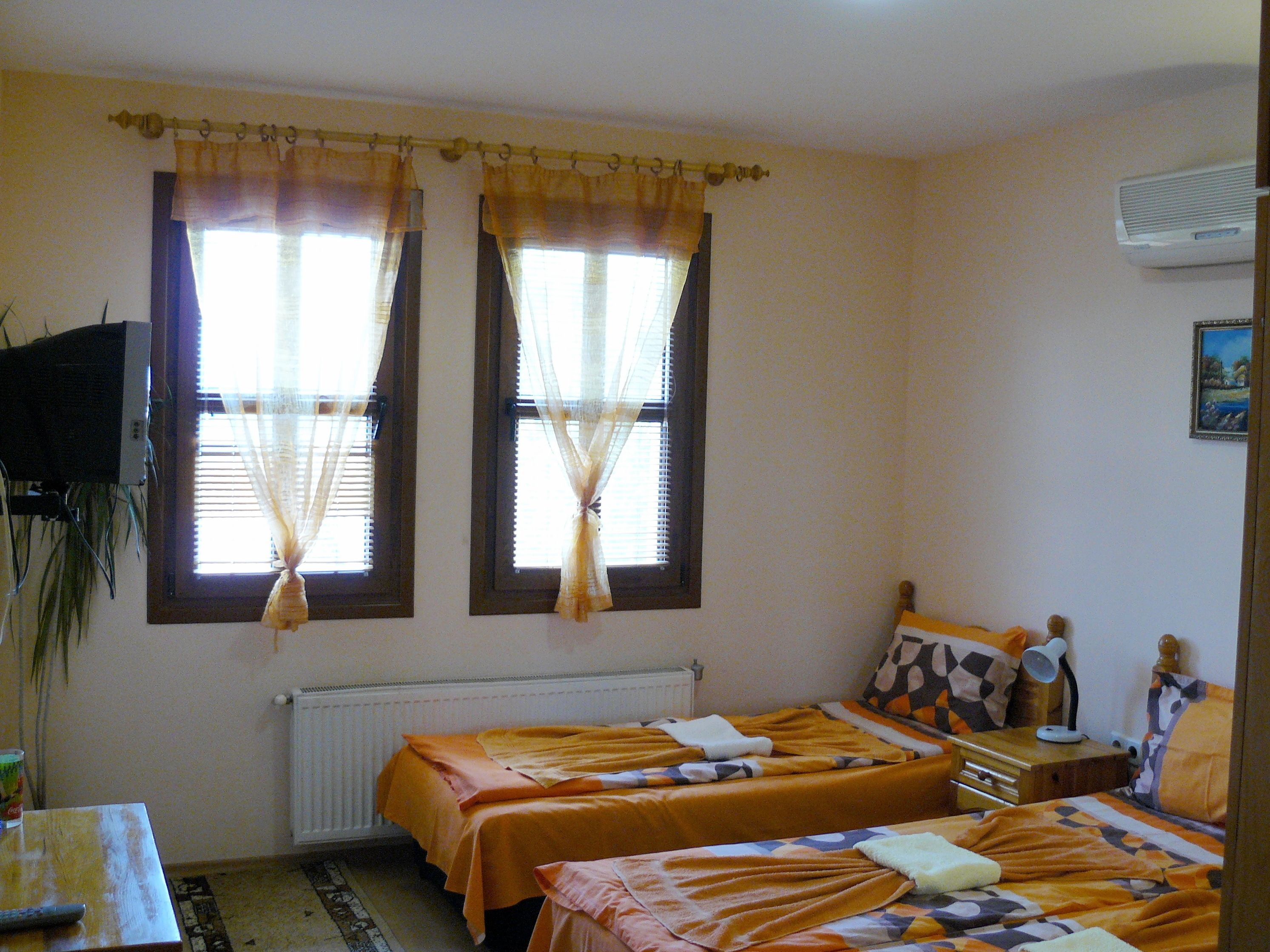 Ein Zimmer mit zwei Betten, einem Heizkörper, einem Fernseher und einem Schreibtisch mit Lampe.