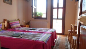 Un dormitorio con dos camas, un escritorio de madera, una silla, un radiador y una ventana con persianas.