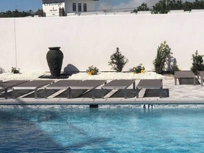 Relax by the serene pool surrounded by sun loungers and a natural stone urn.