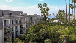 A multi-story hotel with balconies, surrounded by lush greenery and palm trees.