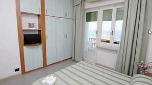 A bedroom with a bed, a TV, a wardrobe, and a window with curtains. - Hotel Eurotel (Grottammare)