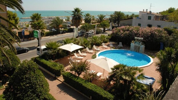 A pool area with lounge chairs and umbrellas, a sign for 'EUROTEL', and a view of the sea. - Hotel Eurotel (Grottammare)