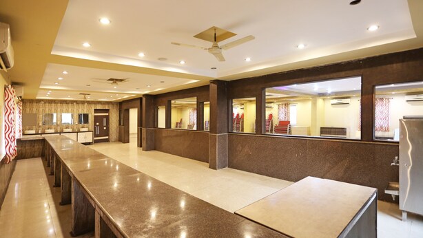 A spacious hotel lobby with a long reception desk, multiple seating areas, and a modern ceiling design. - OYO 10188 Hotel DS Grand Inn (Ramachandrapuram)