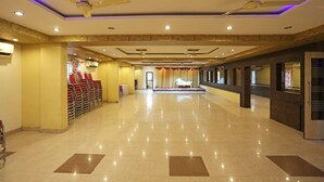 A spacious hotel lobby with a polished floor, ceiling fans, and a seating area with red chairs. - OYO 10188 Hotel DS Grand Inn (Ramachandrapuram)