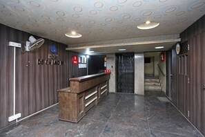 A hotel reception area with a wooden reception desk, a clock, and a reception sign. - OYO 10188 Hotel DS Grand Inn (Ramachandrapuram)