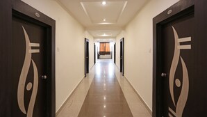 A long, narrow hallway with dark wooden doors featuring a simple design. - OYO 10188 Hotel DS Grand Inn (Ramachandrapuram)