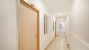 A corridor with wooden doors and windows, leading to a room. - OYO 10235 Oyster Transit Hotels (Hyderabad)