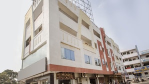 A multi-story building with a hotel on the ground floor, featuring a modern facade, large windows, and a visible staircase leading to the upper floors. - OYO 10235 Oyster Transit Hotels (Hyderabad)