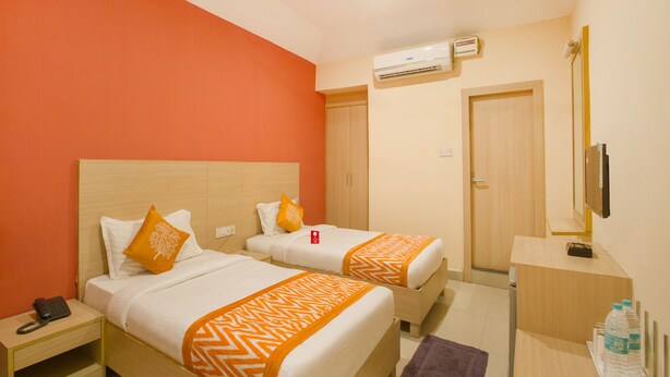 A hotel room with two beds, an air conditioning unit, a desk with a mirror, and a telephone on the nightstand. - OYO 10235 Oyster Transit Hotels (Hyderabad)