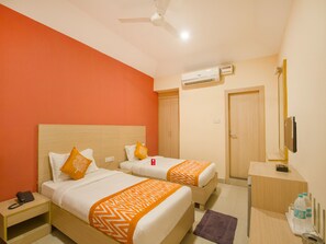 Une chambre d’hôtel avec deux lits, un appareil de climatisation, un bureau avec un miroir et un téléphone sur la table de chevet.