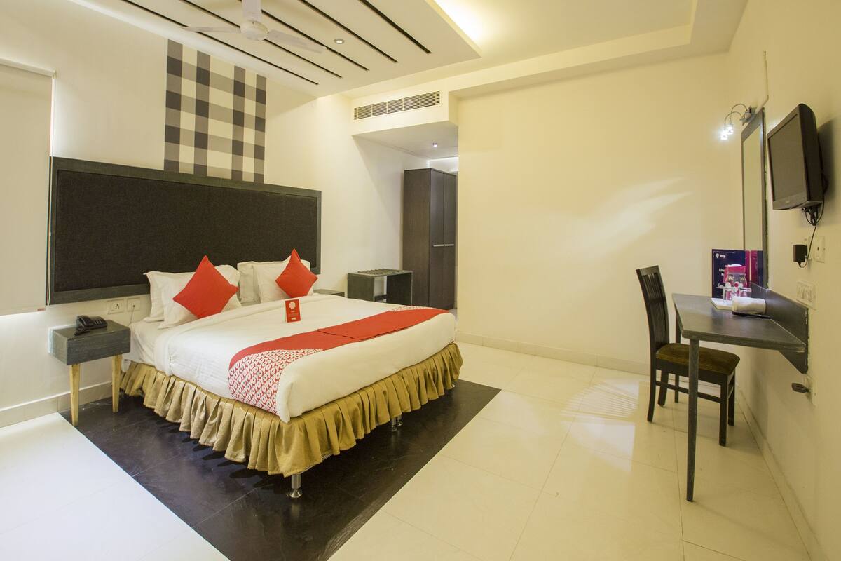 A modern hotel room with a large bed, a desk, and a TV.