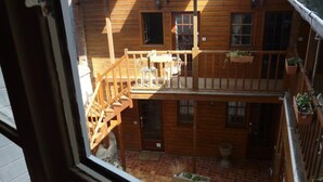 Un bâtiment en bois à deux étages, doté d’un balcon, d’un escalier et d’une petite cour.