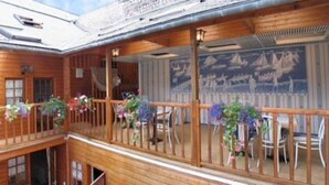 Un bâtiment en bois doté d’un balcon orné de fleurs et d’une fresque représentant des voiliers.