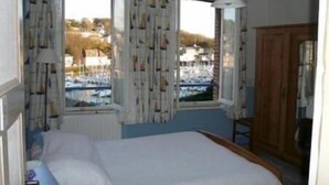 Une chambre à coucher avec un lit, une armoire en bois et une fenêtre avec des rideaux.
