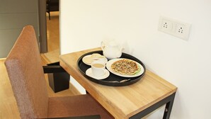 Une petite table à manger sur laquelle se trouve un plateau avec une théière, des tasses et une assiette de nourriture.