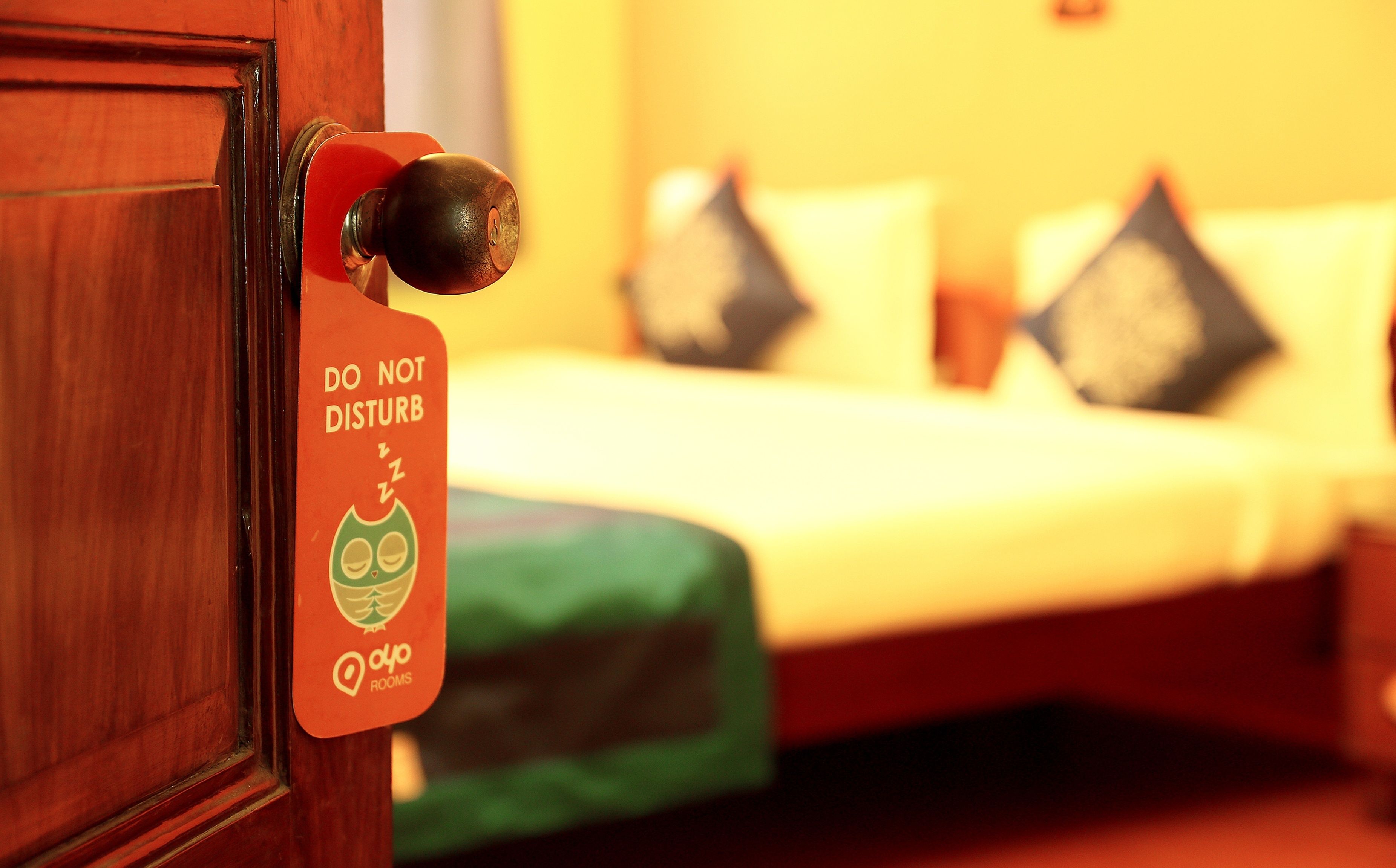 A hotel room door with a 'DO NOT DISTURB' sign featuring a sleeping owl and the logo 'Oyo Rooms'.