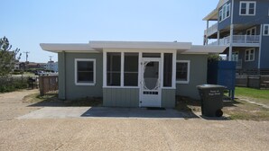 A small, single-story building with a front door, windows, and a small porch. - Summer Special/RIGHT ACROSS from OCEAN/Fenced yard/pet friendly  (Nags Head)