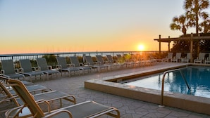 Zona junto a la piscina con sillones de descanso y piscina al atardecer.